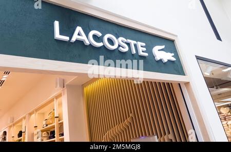 Yerevan, Armenia, December 17, 2022: Illuminated logo of Lacoste store. Lacoste brand logo facade shop sign text on wall store front boutique Stock Photo