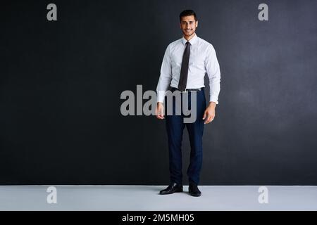 Poised for success. Studio portrait of a young businessman standing against a black background. Stock Photo