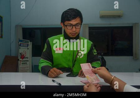 Malang, Indonesia. 29th Dec, 2022. One of the online drivers received assistance in the form of cash of 600,000 Rupiah in Malang. This assistance is the inflationary impact of the increase in fuel oil in Indonesia (Photo by Moch Farabi Wardana/Pacific Press) Credit: Pacific Press Media Production Corp./Alamy Live News Stock Photo