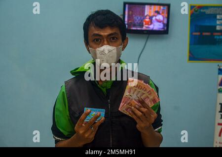 Malang, Indonesia. 29th Dec, 2022. One of the online drivers received assistance in the form of cash of 600,000 Rupiah in Malang. This assistance is the inflationary impact of the increase in fuel oil in Indonesia (Photo by Moch Farabi Wardana/Pacific Press) Credit: Pacific Press Media Production Corp./Alamy Live News Stock Photo