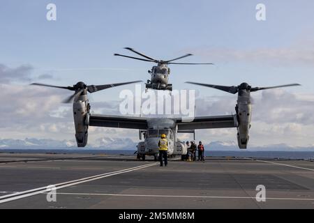 A British Royal Navy Merlin Mk2 helicopter takes off as a U.S. Marine Corps MV-22B Osprey is refueled on the HMS Prince of Wales during Exercise Cold Response 2022, Norwegian Sea, March 26, 2022. The Osprey is assigned to Marine Medium Tiltrotor Squadron 261, 2d Marine Aircraft Wing. Exercise Cold Response ’22 is a biennial exercise that takes place across Norway, with participation from each of its military services, as well as from 26 additional North Atlantic Treaty Organization allied nations and regional partners. Stock Photo