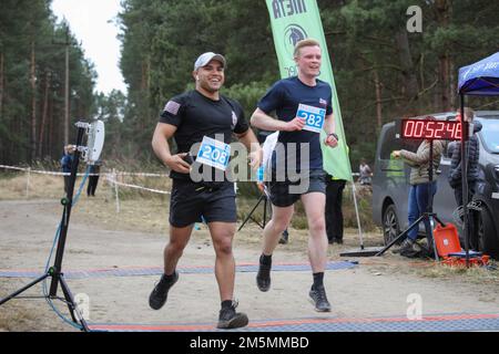 U.S. Army 1st Lt. Rafael Vega assigned to Area Support Group – Poland, crosses the finish line with Flight Lieutenant Pete Wilson of the British Royal Air Force at the 78th Anniversary of “The Great Escape” memorial run in Zagan, Poland, March 26, 2022. Soldiers of the 1st Armored Brigade Combat Team, 1st Infantry Division, participated in a static display and 10K memorial run during the 78th Anniversary of “The Great Escape”. Stock Photo