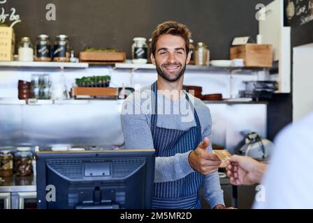 Service with a smile. a handsome young businessman taking payment from a customer. Stock Photo