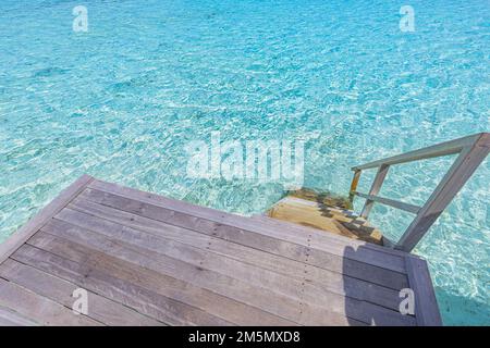 Wooden platform with steps to azure sea water in Maldives islands. Stairway goes down to the ocean lagoon from overwater villa, summer vacation Stock Photo