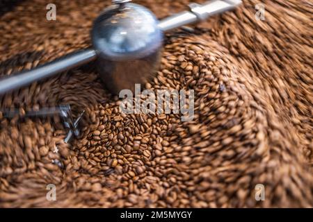 Best coffee background. Freshly roasted coffee beans in motion. Artistic hot beverage closeup concept. Coffee roaster cylinder roasting and mixing Stock Photo