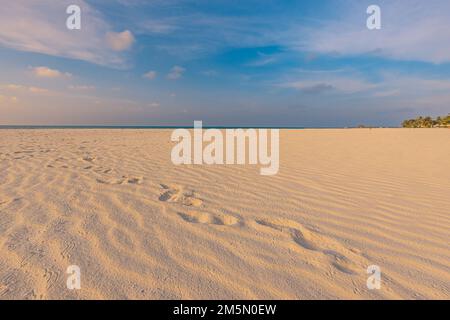 Beach background with footprints in sand closeup. Concept for travel vacation. Inspirational relaxing beach, wave and footprints at sunset time Stock Photo
