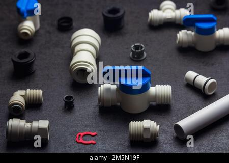 Detail of plastic plumbing, air product, pipe and tools. Valves, elbow and tee with locking clip on black background. Fitting industry Stock Photo