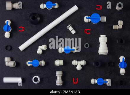 Top view photo of plastic plumbing, air product, pipe and tools. Valves, elbow and tee with locking clip on black background. Fitting industry Stock Photo