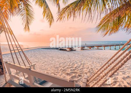 Romantic couple swing close to calm sea and tropical islands shore. Exotic paradise beach landscape, palm trees, sunset sky and summer landscape view Stock Photo