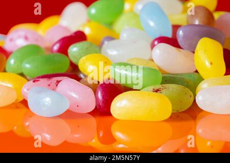 Jelly beans sweets candy piled on an orange background. High sugar unhealthy food concept Stock Photo