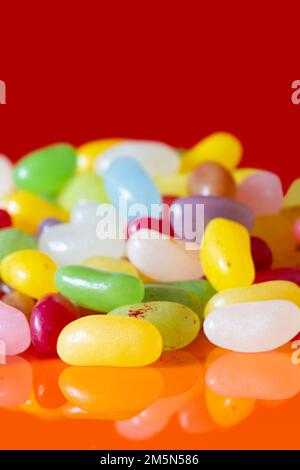 Jelly beans sweets candy piled on an orange background. High sugar unhealthy food concept Stock Photo