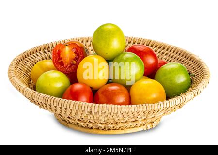 Side view closeup of freshly harvested multi colored cherry tomatoes in bamboo basket isolated on white background with clipping path. Stock Photo