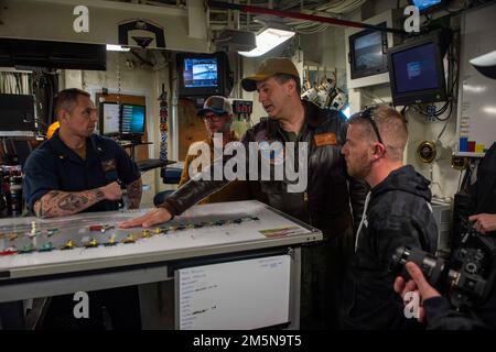 220329-N-OL632-1068 NAVAL STATION NORFOLK (March 29, 2022) Capt. Robert Aguilar, commanding officer of USS George H.W. Bush (CVN 77), talks about flight deck operations with NASCAR Hall of Famer Dale Earnhardt Jr. and NASCAR Xfinity Series driver Justin Allgaier during a visit to the ship, March 29, 2022. George H.W. Bush provides the national command authority flexible, tailorable war fighting capability as the flagship of the carrier strike group which maintains maritime stability and security in order to ensure access, deter aggression and defend U.S., allied and partner interests. Stock Photo