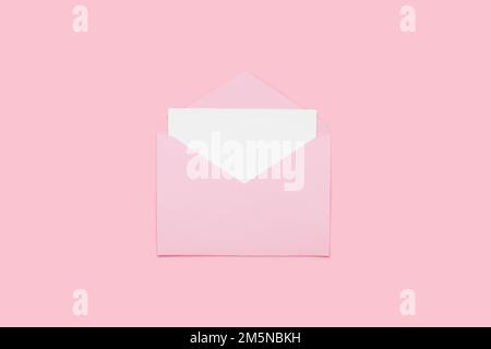 Closeup on blank empty white paper card in pink opened envelope isolated on pink pastel color background. Love letter minimal concept. Conceptual layout template with text place on postcard. Mock-up  Stock Photo