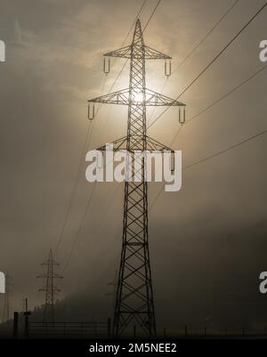 High-voltage electricity pylons in autumn fog Stock Photo