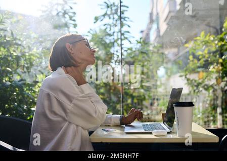 Tired stressed woman suffering from neckpain working from home office sitting at table. Overworked young aged lady massaging neck feeling hurt pain Stock Photo