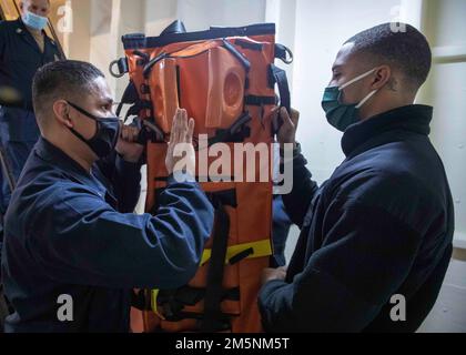 220225-N-TI693-1096    MEDITERRANEAN SEA (Feb. 25, 2022) - Retail Services Specialist 3rd Class Christian Ambriz, left, from Lawton, Oklahoma, discusses the stretcher bearer training with Retail Services Specialist Seaman Jayson Doby, from Damville, Virginia, during a medical training team drill aboard the Expeditionary Sea Base USS Hershel 'Woody' Williams (ESB 4), Feb. 25, 2022. Hershel 'Woody' Williams is on a scheduled deployment in the U.S. Sixth Fleet area of operations in support of U.S. national interests and security in Europe and Africa. Stock Photo