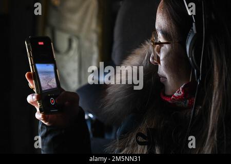 A Yokota spouse takes a photo from inside of a C-130J Super Hercules assigned to the 36th Airlift Squadron during a Spouse Orientation Flight opportunity at Yokota Air Base, Japan, Feb. 25, 2022. The spouses had the opportunity to fly on the C-130, UH-1N Huey and C-12 Huron as part of the orientation day. Stock Photo