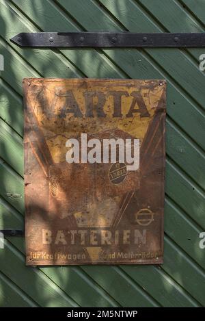 Old rusted tin sign from Varta Batterien on a stable door, Bavaria, Germany Stock Photo