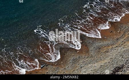 Gentle waves breaking on a sand and shingle beach on the coast  close to Durdle Door in Dorset. England Stock Photo