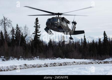 An Alaska Army National Guard UH-60L Black Hawk helicopter operated by air crew assigned to the 207th Aviation Troop Command approaches the landing zone at Camp Mad Bull while supporting a joint operations field training exercise at Joint Base Elmendorf-Richardson, Alaska, Feb. 26, 2022. Air Force engineers from the 673d Civil Engineer Group and Alaska Army National Guardsmen with the 207th Engineer Utility Detachment conducted the joint training to demonstrate mission-readiness skills in arctic conditions. Stock Photo