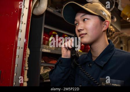 220223-N-XB010-1005 EAST CHINA SEA (Feb. 23, 2022) Ensign Allysin Marsico, from Columbus, Ohio, communicates with the Central Control Station aboard USS New Orleans (LPD 18) from a repair locker during a general quarters drill. New Orleans, part of the America Amphibious Ready Group, along with the 31st Marine Expeditionary Unit, is operating in the U.S. 7th Fleet area of responsibility to enhance interoperability with allies and partners and serve as a ready response force to defend peace and stability in the Indo-Pacific region. Stock Photo