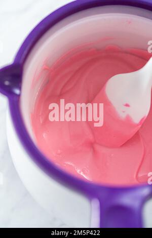 Melting pink chocolate melts to make mini pink chocolates Stock Photo -  Alamy