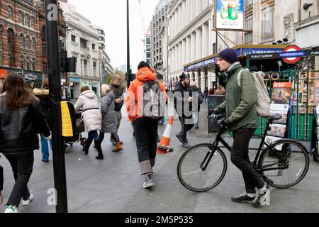 People pedestrians cyclist walking bike on pavement at corner Tottenham Court Road tube station underground sign London UK 2022  KATHY DEWITT Stock Photo