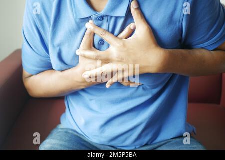 young man suffering pain in heart and holding chest with hand  Stock Photo