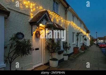 Christmas lights and wreath at dusk on houses in Odiham High Street, a Hampshire village, England, UK, at dusk during December Stock Photo