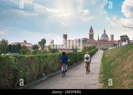 Cycling Italy, rear view in summer of two women cycling towards the scenic Renaissance era city of Mantua (Mantova) in Lombardy, Italy Stock Photo