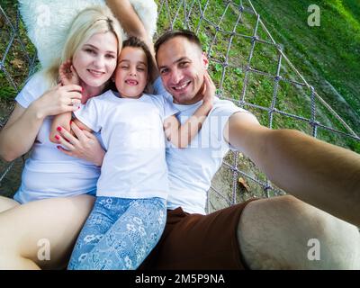 Family Relaxing In Garden Hammock Together Stock Photo