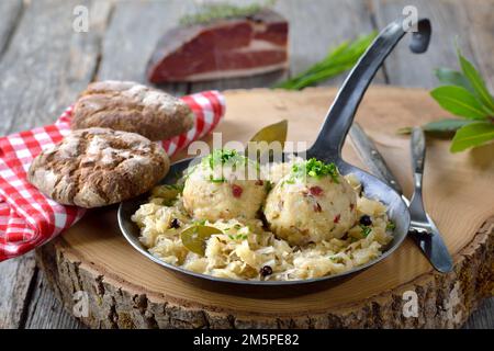 Delicious South Tyrolean bacon dumplings served on sauerkraut in an iron frying pan Stock Photo