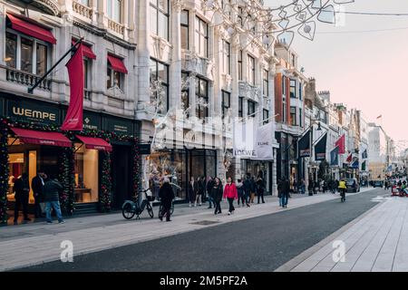 London, UK - December 26, 2022: People walking past the high end stores on New Bond Street, one of the most famous streets for luxury shopping in Lond Stock Photo