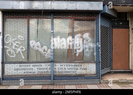A closed down shop with its windows covered with bill posters and graffiti, High Street, Penge, London, UK.  25 Dec 2022 Stock Photo