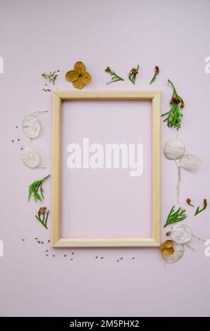Empty wooden frame on pink background with dried lunaria and gardenia flowers and thuja branches. Mockup poster frame close up in neutral color, minim Stock Photo