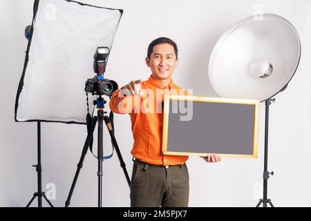 vlogger standing with hand pointing at camera while holding blackboard Stock Photo