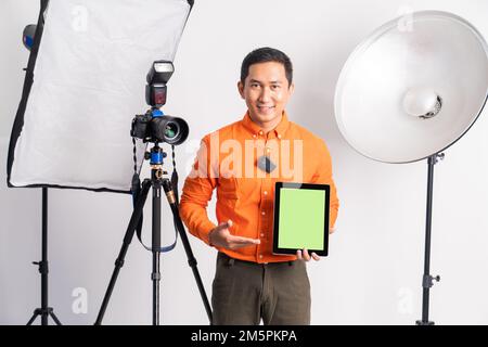 vlogger standing with hand pointing at screen while holding tablet Stock Photo