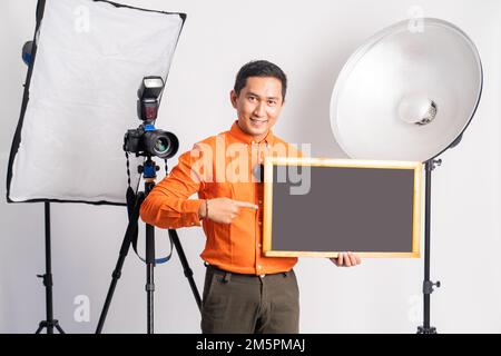 vlogger standing with pointing hand while holding blackboard with lighting Stock Photo