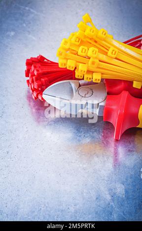 Nippers tying cables on scratched metallic background. Stock Photo