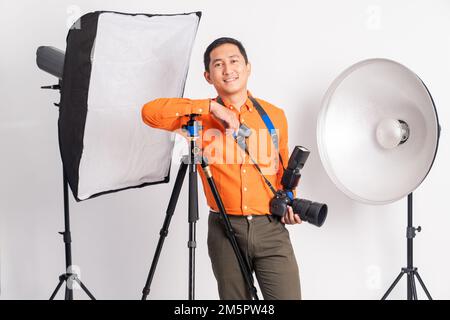 smiling man leaning on tripod holding camera with photographic equipment Stock Photo