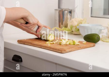 woman hands cutting vegetables at kitchen. Healthy and easy food. Close-up sliced vegetable marrow Stock Photo