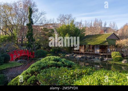 Landscape view of the Pierre Baudis japanese garden with traditional red wooden bridge and house in Compans-Caffarelli public park, Toulouse, France Stock Photo