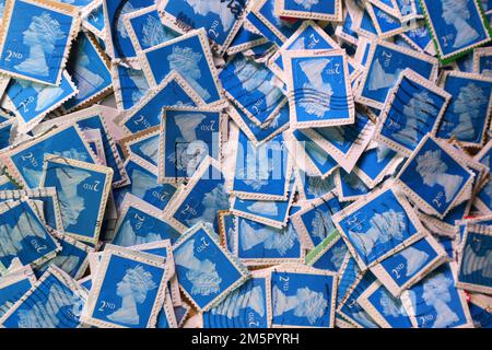 Used UK franked postage stamps being collectd for a charity contribution. A colourful selection of use British Royal Mail postage stamps in close up. UK Britain. Blue Second class (2nd ) stamps Stock Photo