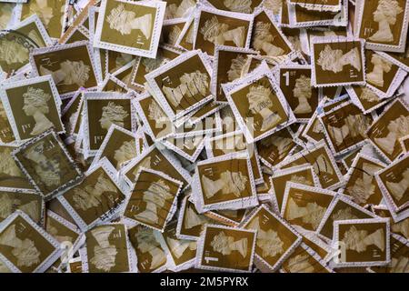 Used UK franked postage stamps being collectd for a charity contribution. A colourful selection of use British Royal Mail postage stamps in close up. UK Britain. Brown First Class (1st ) Stamps Stock Photo