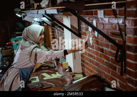 Craftswoman in veil makes sticky notes on wall while working Stock Photo