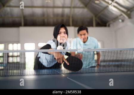 Female player in hijab hits the ball over the net Stock Photo