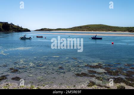 Three small boats are anchored in Clonakilty Bay on a sunny spring day. Irish sea landscape at low tide, shallow water, boat on sea. Stock Photo