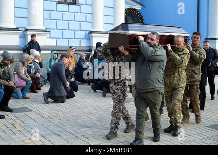 KYIV, UKRAINE - DECEMBER 30, 2022 - People kneel to show their respect as servicemen carry the coffin with the body of former political prisoner Henna Stock Photo