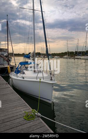 Sailing yacht moored on a wooden pontoon in a tranquil setting. Stock Photo